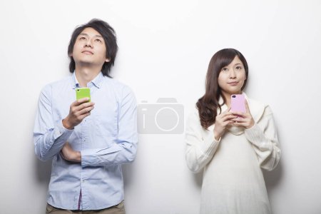 Photo for Young asian couple with smartphones - Royalty Free Image