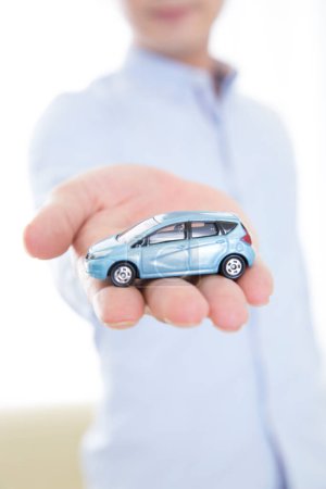 Téléchargez les photos : Homme d'affaires main tenant une voiture jouet - en image libre de droit
