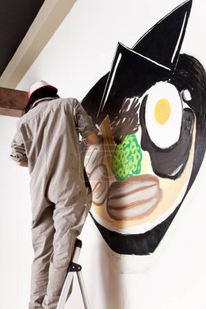 Foto de Joven trabajadora dedcorating pared en moderno restaurante - Imagen libre de derechos