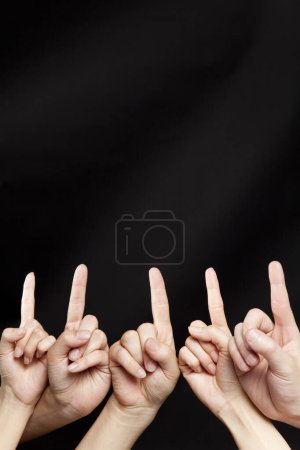 Téléchargez les photos : Mains pontant avec les doigts vers le haut sur fond noir - en image libre de droit