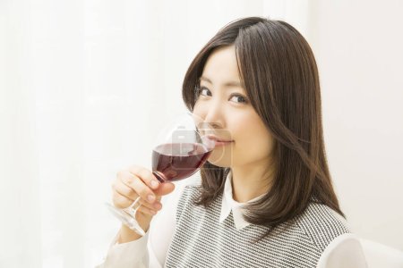 Foto de Hermosa mujer japonesa bebiendo vino en casa - Imagen libre de derechos