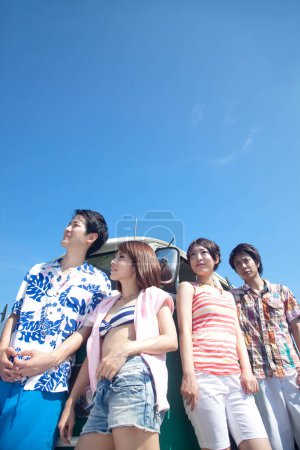 Foto de Grupo de amigos divirtiéndose en la playa, de pie junto a la van - Imagen libre de derechos