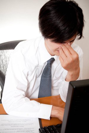 Foto de Joven hombre de negocios con dolor de cabeza en la oficina - Imagen libre de derechos