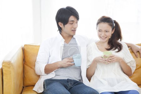 Téléchargez les photos : Couple heureux prenant un café sur le canapé - en image libre de droit