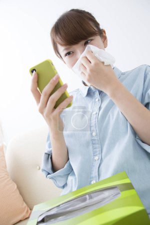 Foto de Mujer asiática con resfriado y gripe usando teléfono inteligente y sosteniendo papel - Imagen libre de derechos