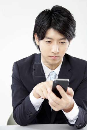 Téléchargez les photos : Homme d'affaires utilisant un téléphone portable au bureau - en image libre de droit