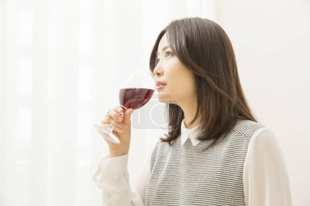 Téléchargez les photos : Belle femme japonaise boire du vin à la maison - en image libre de droit