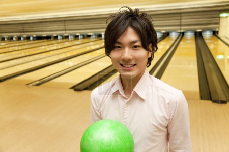Foto de Asiático hombre celebración bowling bola en club - Imagen libre de derechos