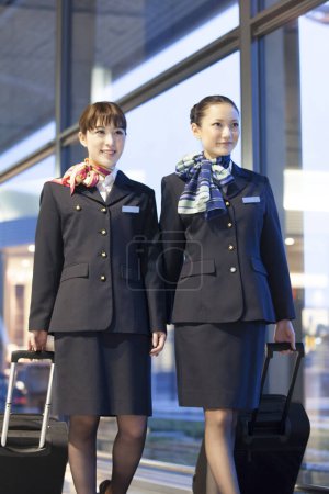 Photo for Two flight attendants walking in airport - Royalty Free Image