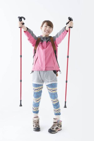 Photo for Studio portrait of smiling Japanese woman hiker with nordic walking poles - Royalty Free Image