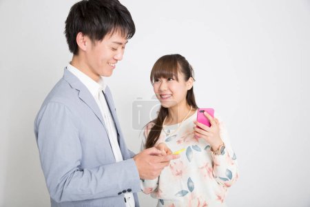 Téléchargez les photos : Jeune asiatique homme et femme avec smartphones sur fond blanc - en image libre de droit
