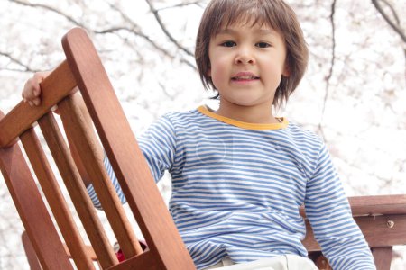 Photo for Portrait of a little boy on chair  in a park - Royalty Free Image