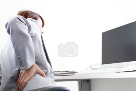 Foto de Empresaria que sufre de dolor de espalda en la oficina - Imagen libre de derechos