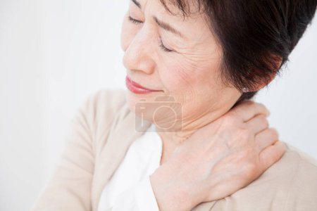 Foto de Retrato de la mujer japonesa mayor que sufre de dolor de hombro sobre fondo blanco - Imagen libre de derechos