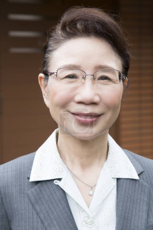 Téléchargez les photos : Mature asiatique femme d'affaires souriant à l'extérieur - en image libre de droit