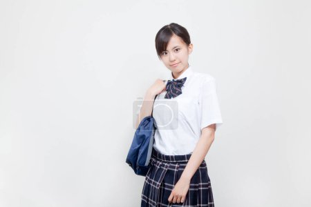 Téléchargez les photos : Portrait studio de jeune fille japonaise en uniforme scolaire avec sac - en image libre de droit