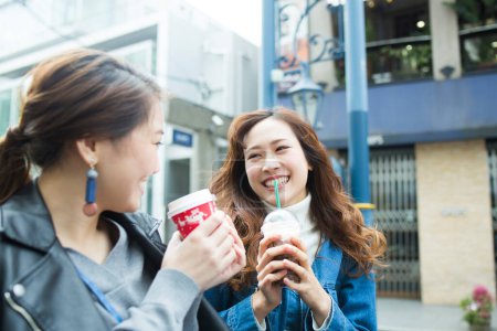 Téléchargez les photos : Deux jeunes amis asiatiques s'amuser ensemble boire du café sur la rue - en image libre de droit