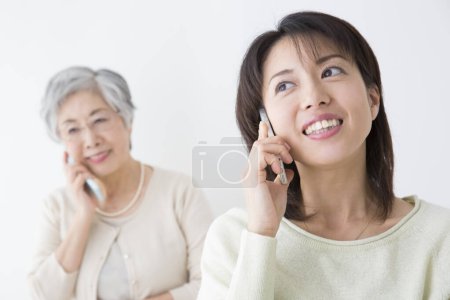 Foto de Asiático senior mujer y joven mujer hablando en móvil - Imagen libre de derechos