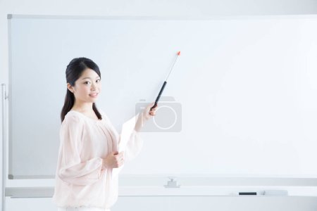 Photo for Asian female teacher  with pointer in classroom - Royalty Free Image