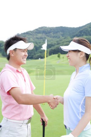 Foto de Pareja joven estrechando la mano en el campo de golf - Imagen libre de derechos
