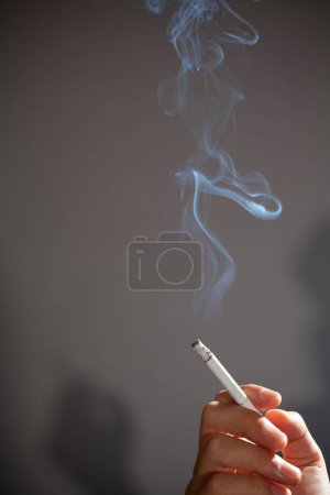 Foto de Mano con cigarrillo sobre fondo gris. concepto de fumar - Imagen libre de derechos