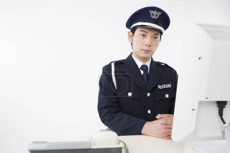 Photo for Studio portrait of Japanese police officer with computer - Royalty Free Image
