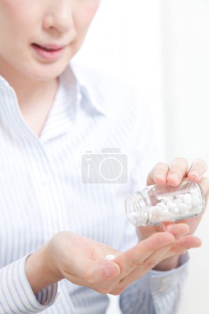 Foto de Mujer tomando pastillas de frasco de vidrio - Imagen libre de derechos