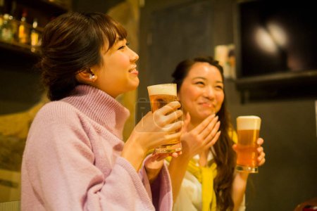 Foto de Jóvenes mujeres japonesas bebiendo cerveza en el bar - Imagen libre de derechos