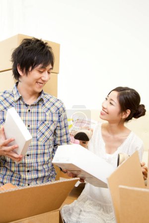 Téléchargez les photos : Couple asiatique avec des boîtes en carton se déplaçant dans une nouvelle maison - en image libre de droit