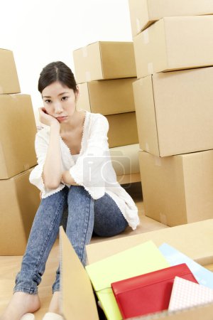 Téléchargez les photos : Jeune femme réfléchie assise avec des boîtes en carton dans une nouvelle maison - en image libre de droit