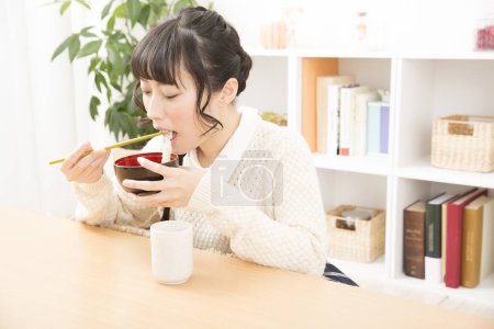 Foto de Hermosa japonesa mujer comer comida en casa - Imagen libre de derechos