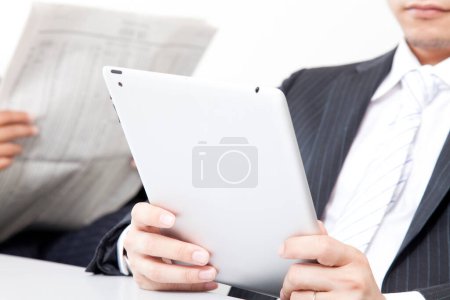 Foto de Cerrar a los hombres de negocios que utilizan la tableta digital, y leer el periódico en la oficina moderna - Imagen libre de derechos