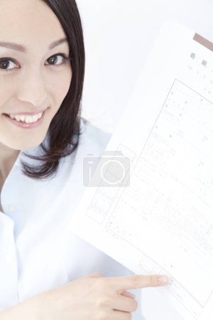 Photo for Young doctor looking at the camera and  showing document - Royalty Free Image