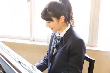 Photo for Japanese female school student playing piano - Royalty Free Image