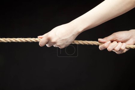 Foto de Mano tirando de una cuerda sobre fondo negro - Imagen libre de derechos