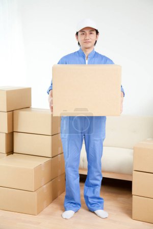 Photo for Young Japanese delivery man with cardboard boxes - Royalty Free Image
