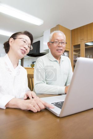 Photo for Senior asian couple using laptop at home - Royalty Free Image