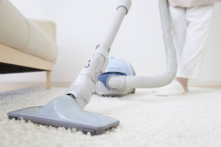 Photo for Asian woman cleaning house at home with vacuum cleaner - Royalty Free Image
