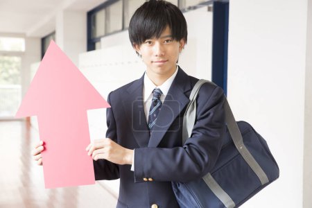 Japanischer Student steht an der Universität und hält roten Pfeil in der Hand 