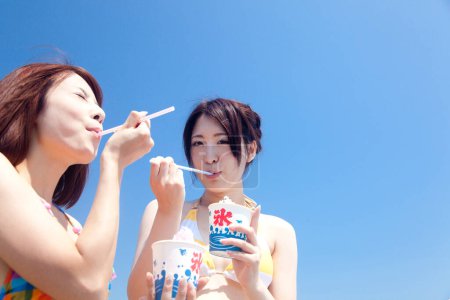 Téléchargez les photos : Femmes asiatiques avec crème glacée sur la plage - en image libre de droit