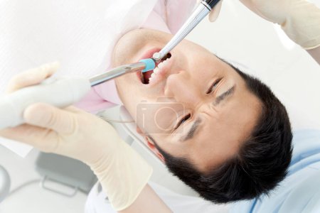 Téléchargez les photos : Dentiste examinant les dents d'un patient de sexe masculin à la clinique - en image libre de droit