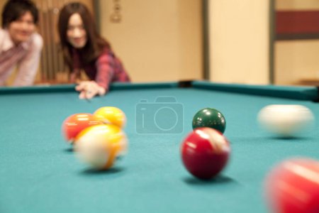 Photo for Happy Japanese young man and woman playing billiard - Royalty Free Image