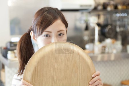 Photo for Woman holding a empty plate in front of a restaurant - Royalty Free Image