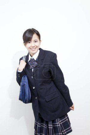 Téléchargez les photos : Portrait studio de jeune fille japonaise en uniforme scolaire avec sac - en image libre de droit