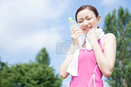 Photo for Young beautiful girl with water after jogging in the park - Royalty Free Image