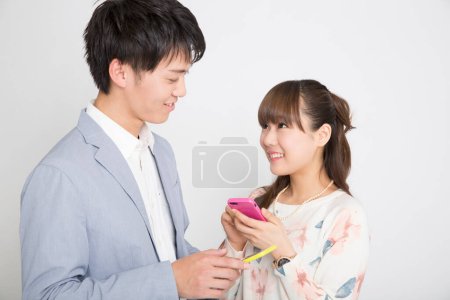 Photo for Young man and young woman with smartphones, studio shot - Royalty Free Image
