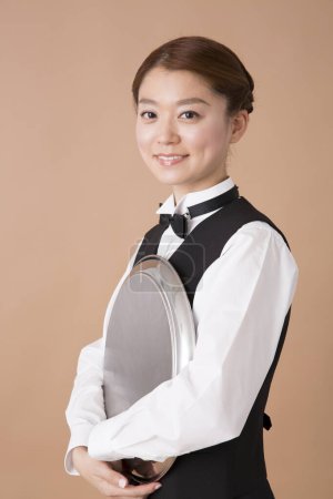 Téléchargez les photos : Portrait studio de jeune belle serveuse japonaise avec plateau en métal - en image libre de droit