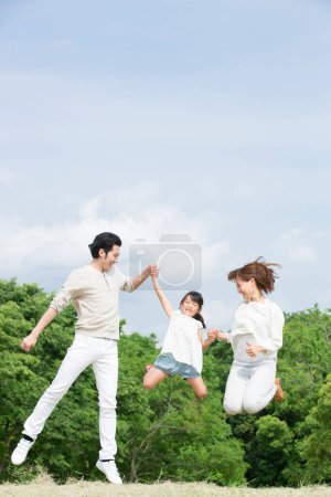 Foto de Familia joven feliz de tres jugando juntos en el prado - Imagen libre de derechos