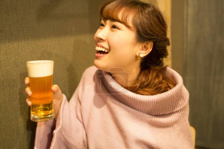 Foto de Joven japonesa con vaso de cerveza en el bar - Imagen libre de derechos