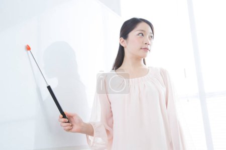 Photo for Woman teacher with pointer at white board - Royalty Free Image